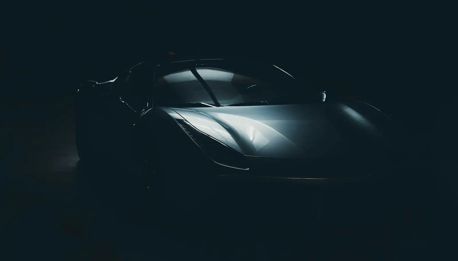 Sports car in a dark studio, light across the hood