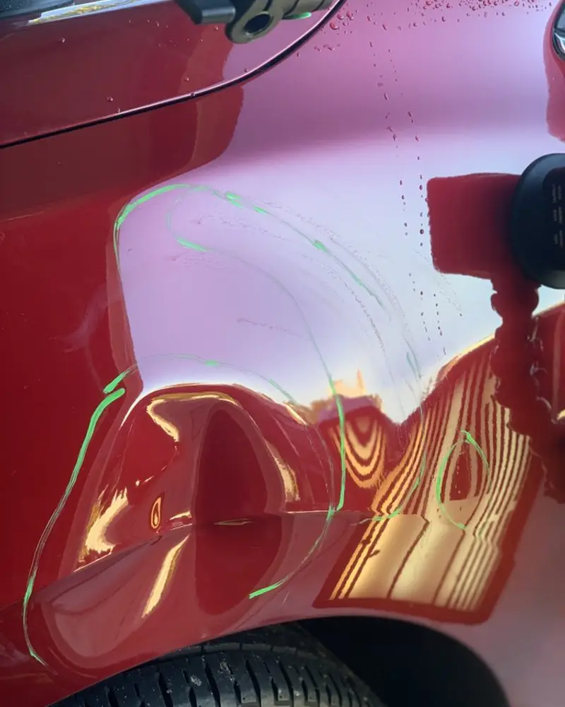 Reflection board lines across a dent on a red panel